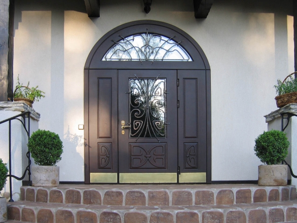 Металлическая дверь со стеклянными вставками в частном доме с защитными коваными элементами