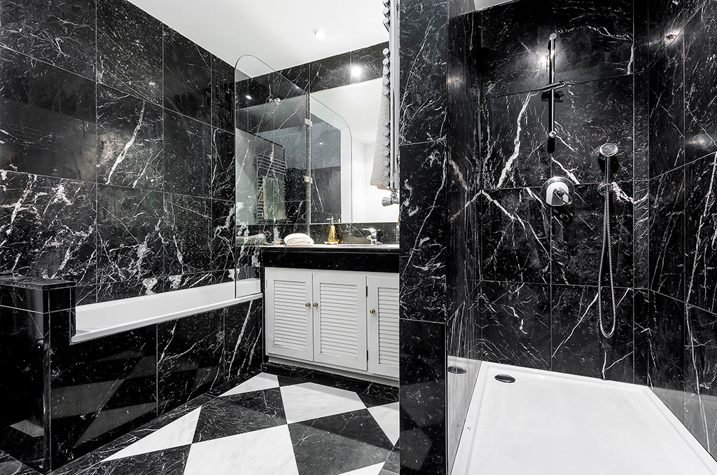 Темный интерьер ванной комнаты с отделкой из мраморных плит большого размера