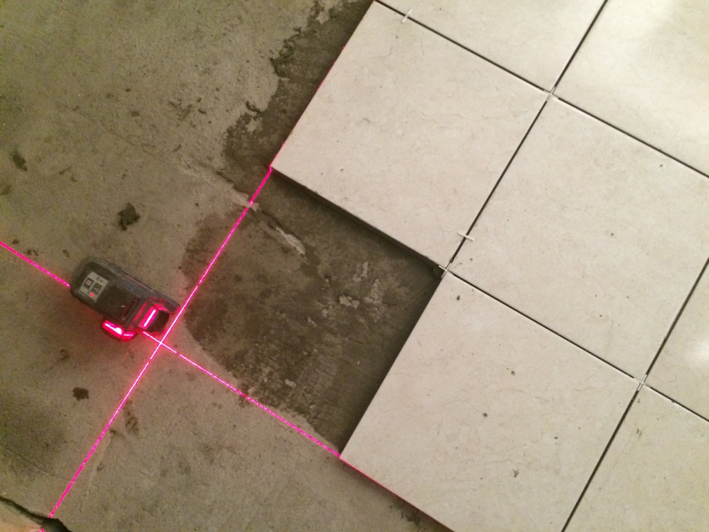 Разметка с помощью строительного лазера перед выкладкой плитки в ванной