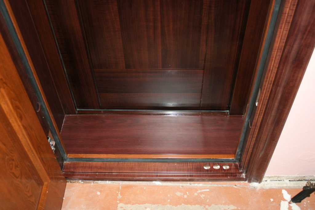 Фигурный порожек у входной двери с отделкой под древесину